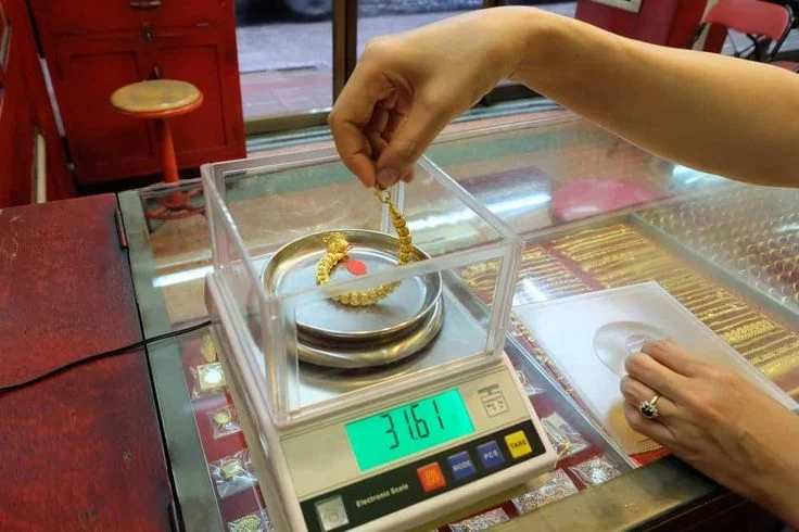 Gold necklace being weighed on a digital jewelry scale